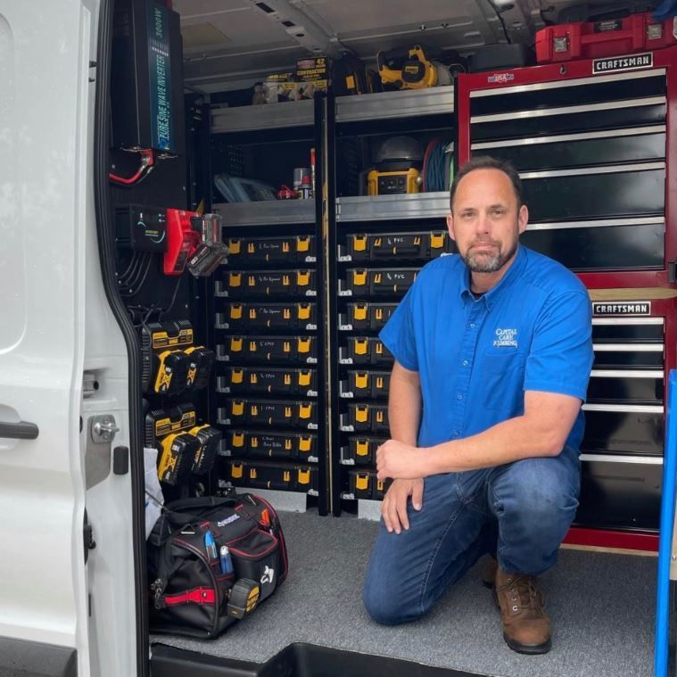 A man is kneeling in the back of a craftsman van