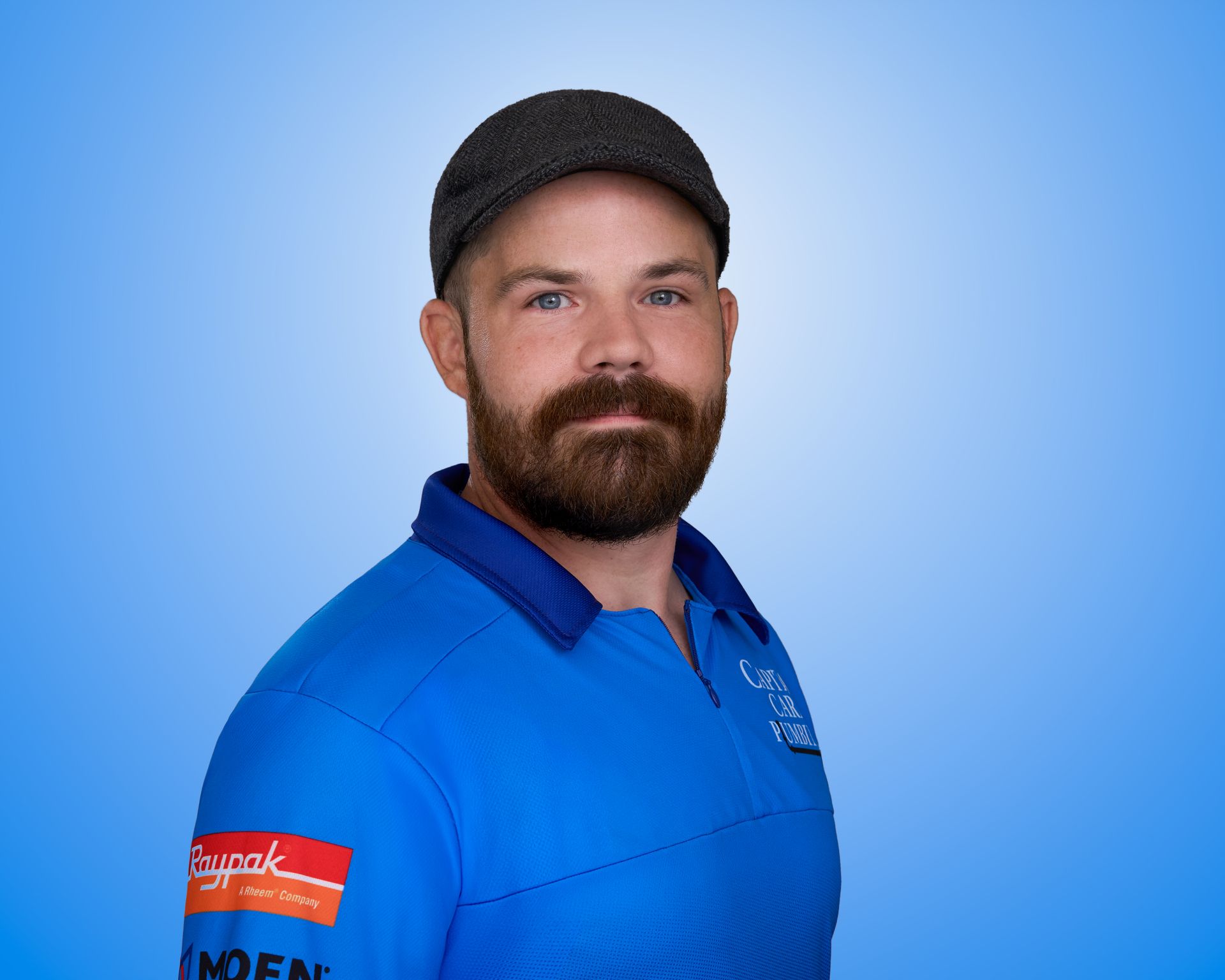 A man with a beard wearing a hat and a blue shirt