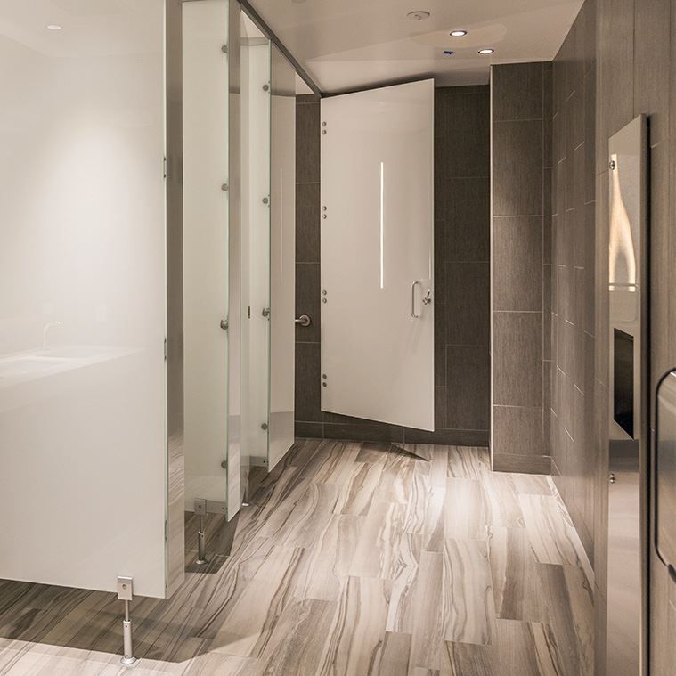 A hallway with a toilet cubicle and a hand sanitizer dispenser