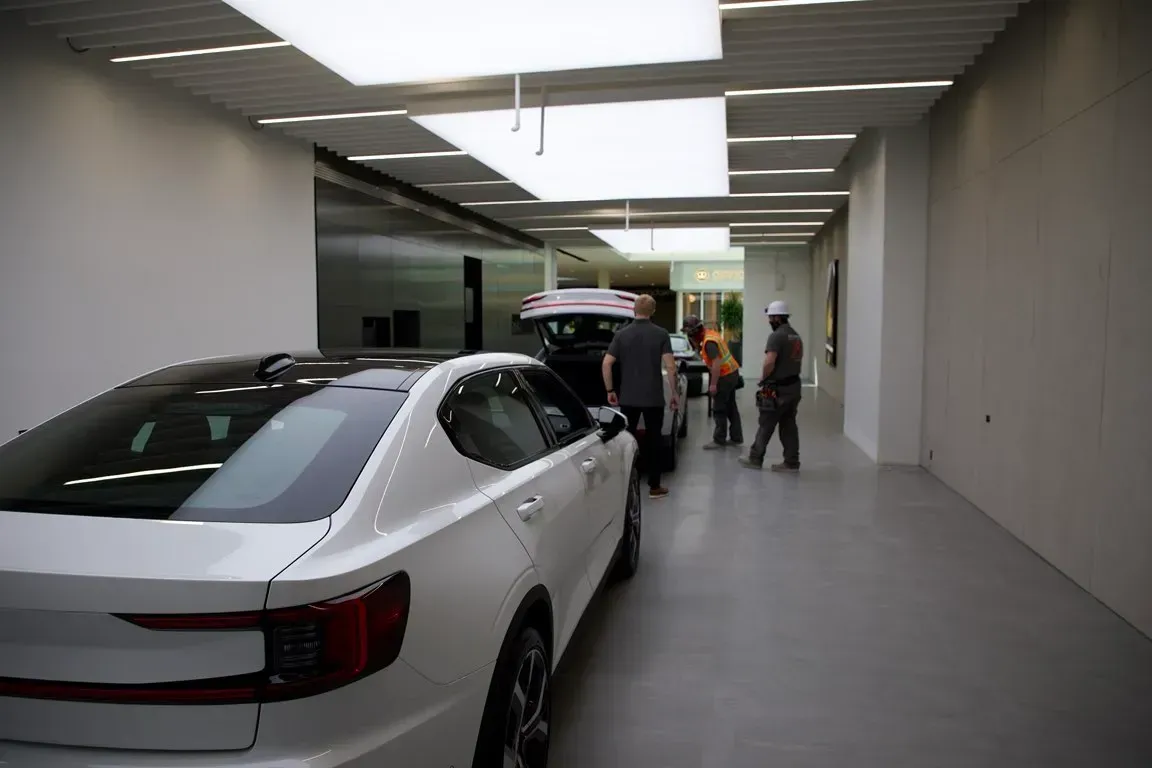 White sedan in a garage with several people gathered near the front of the car