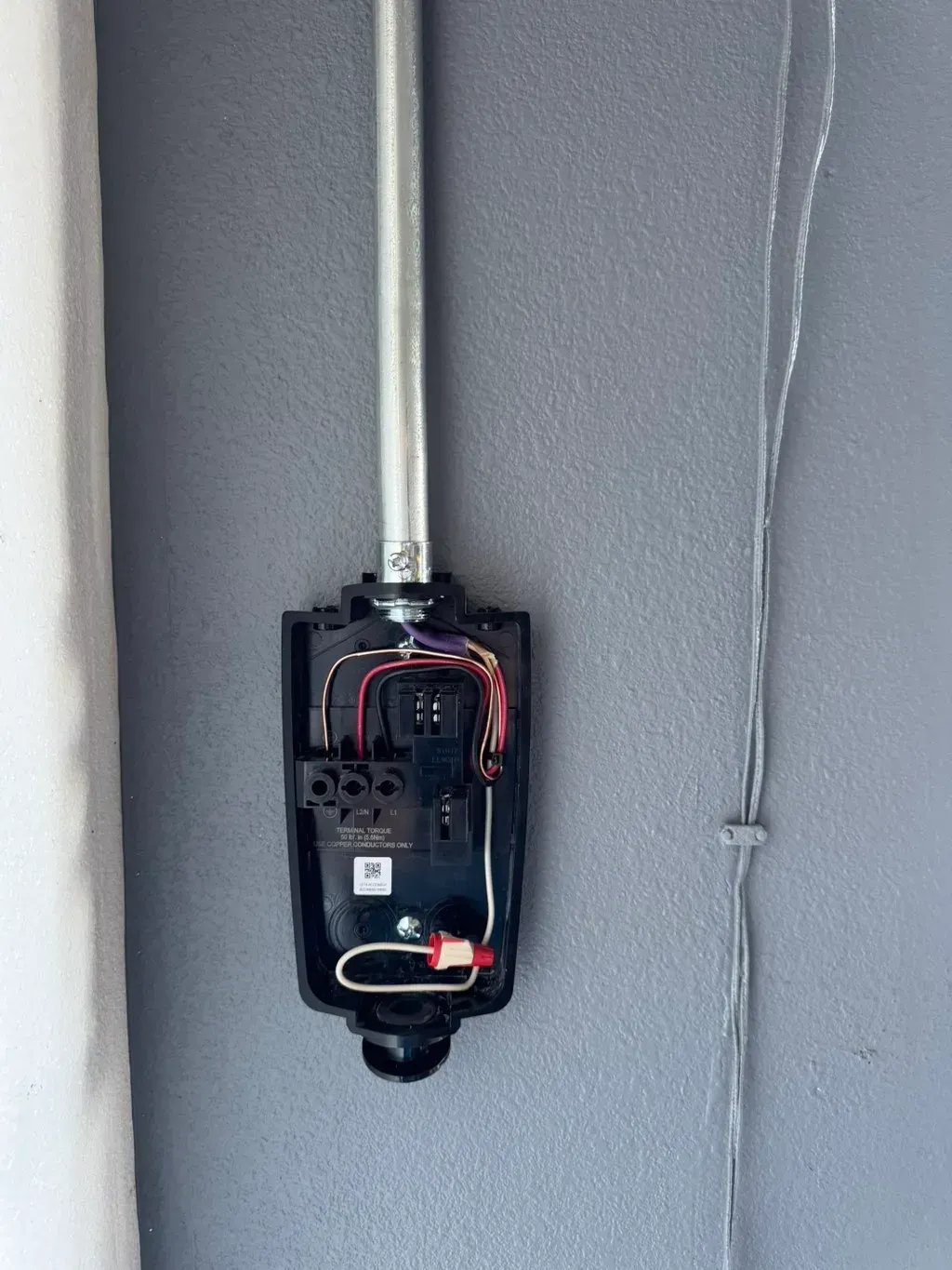Open electrical panel with exposed wiring on a gray wall