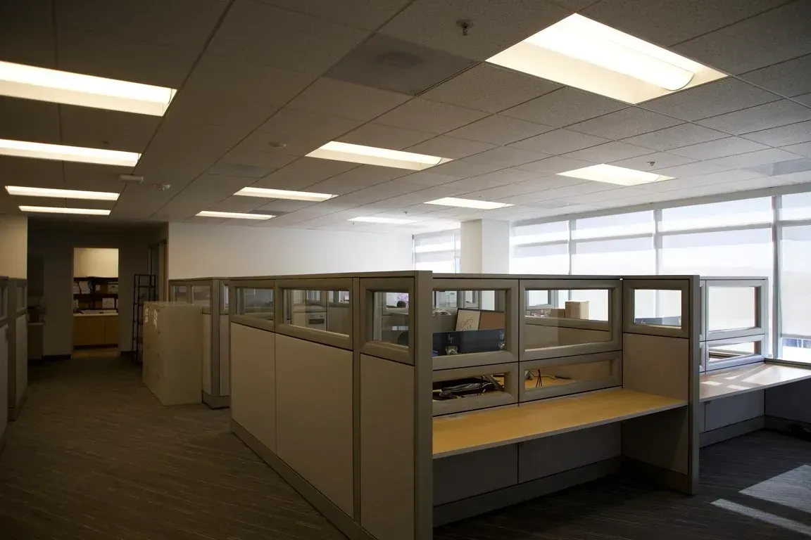 Empty office cubicles under bright fluorescent lights in a modern workspace