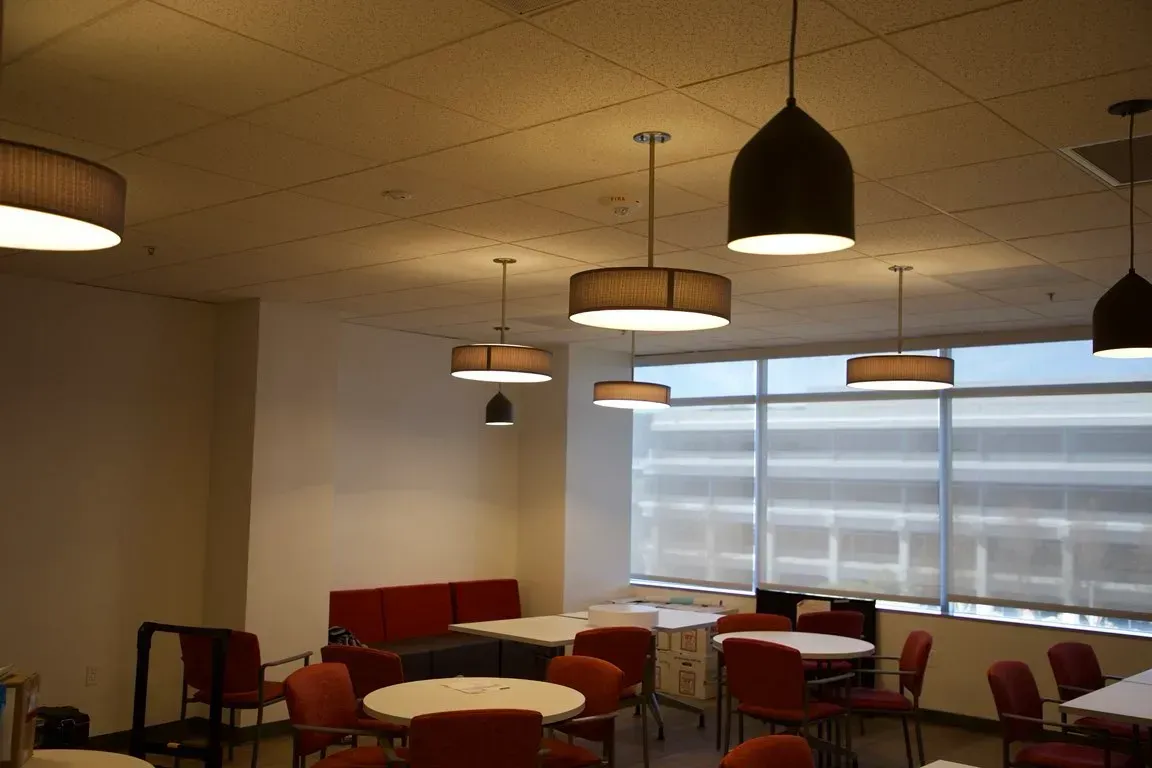Quiet lounge with red chairs and tables, pendant lights, and large windows.
