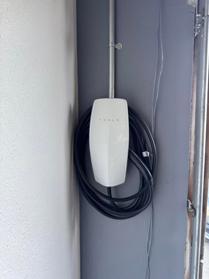Wall-mounted white device with coiled black cable in a gray utility cabinet