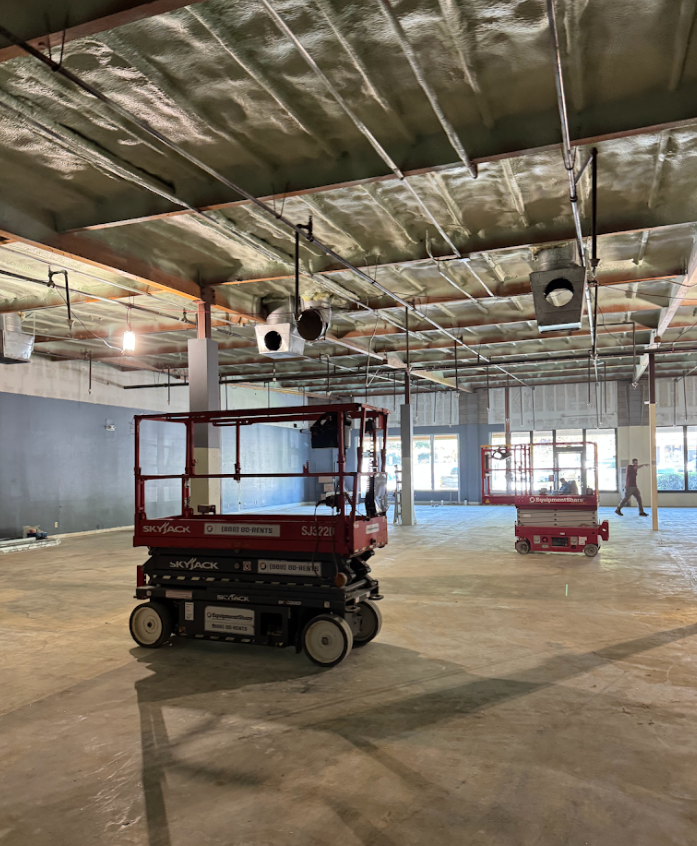 Empty warehouse with two red scissor lifts under exposed ceiling beams