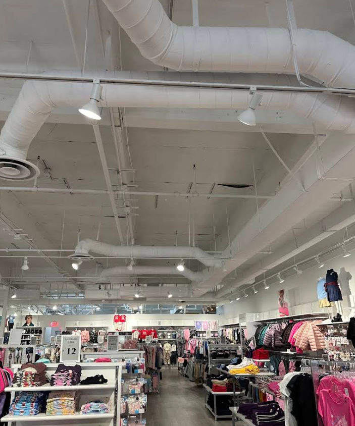 Clothing store interior with racks of clothes and bright ceiling lights