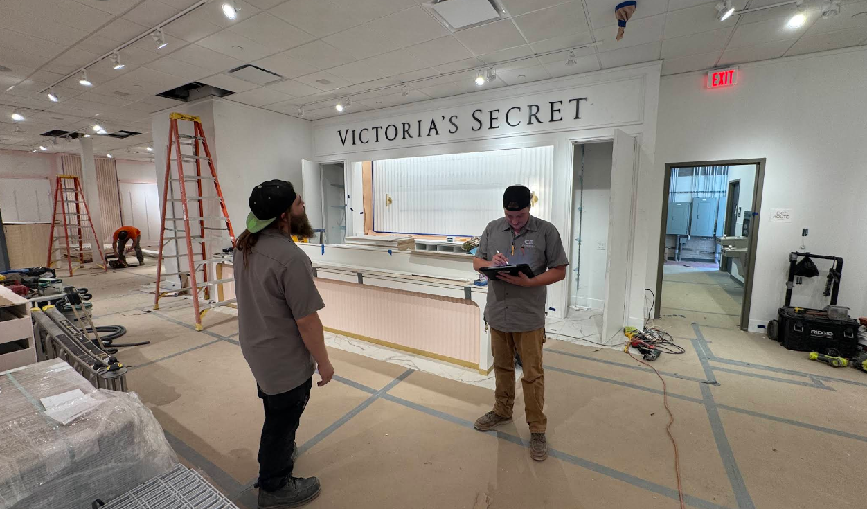 Victoriaβs Secret store under renovation, with two workers and ladders in a partially stripped interior.