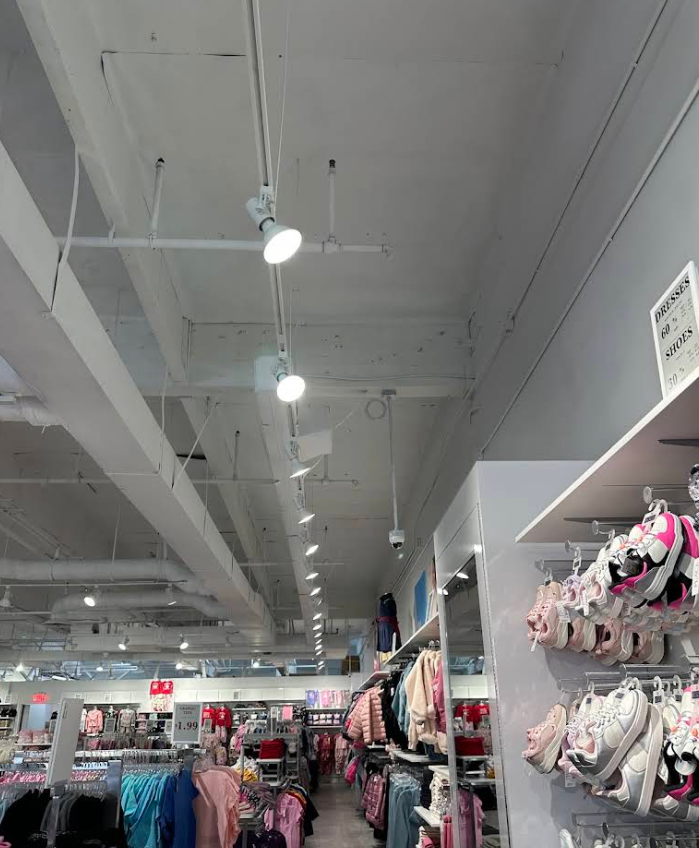 Clothing store aisle with hanging lights, shelves of merchandise, and racks of colorful apparel and shoes