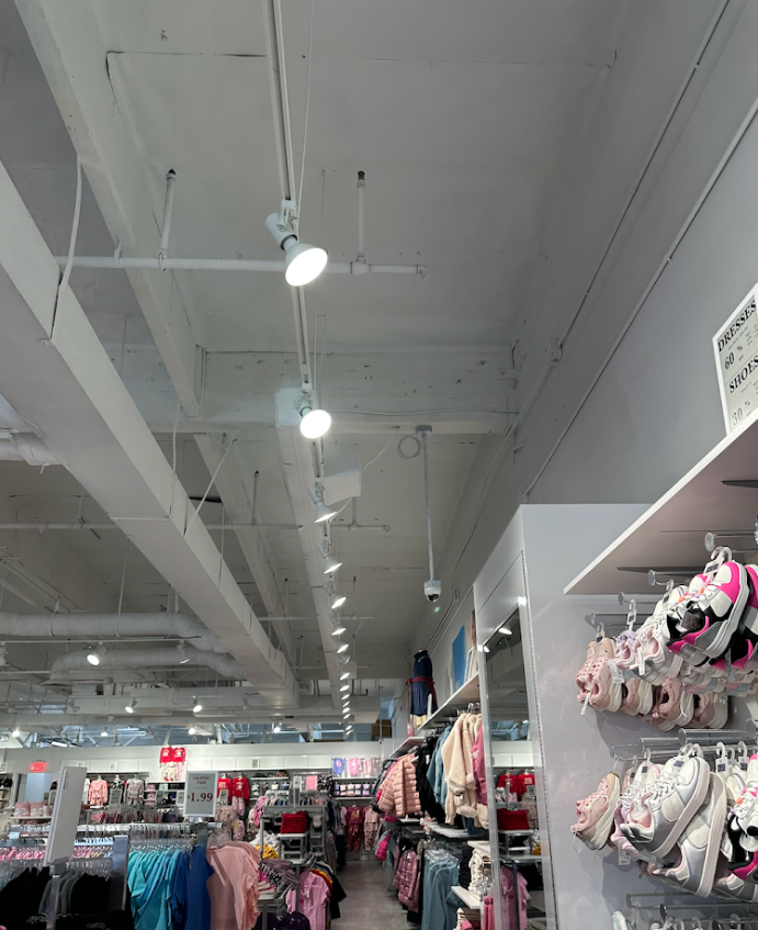 Clothing store interior with white ceiling lights and racks of colorful clothes and shoes