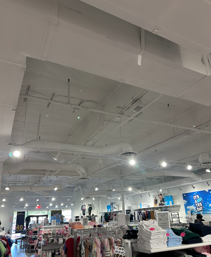 Retail store interior with white exposed ceiling, bright lights, and clothing racks below