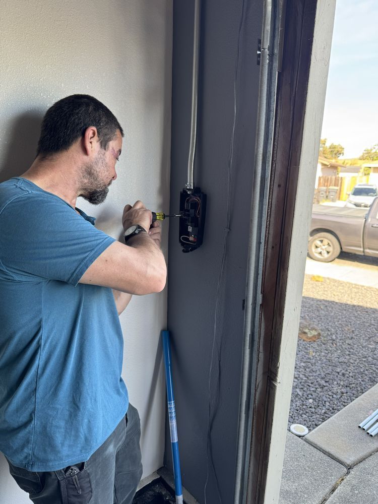 Man using a power screwdriver to install a door lock on a partially open doorway