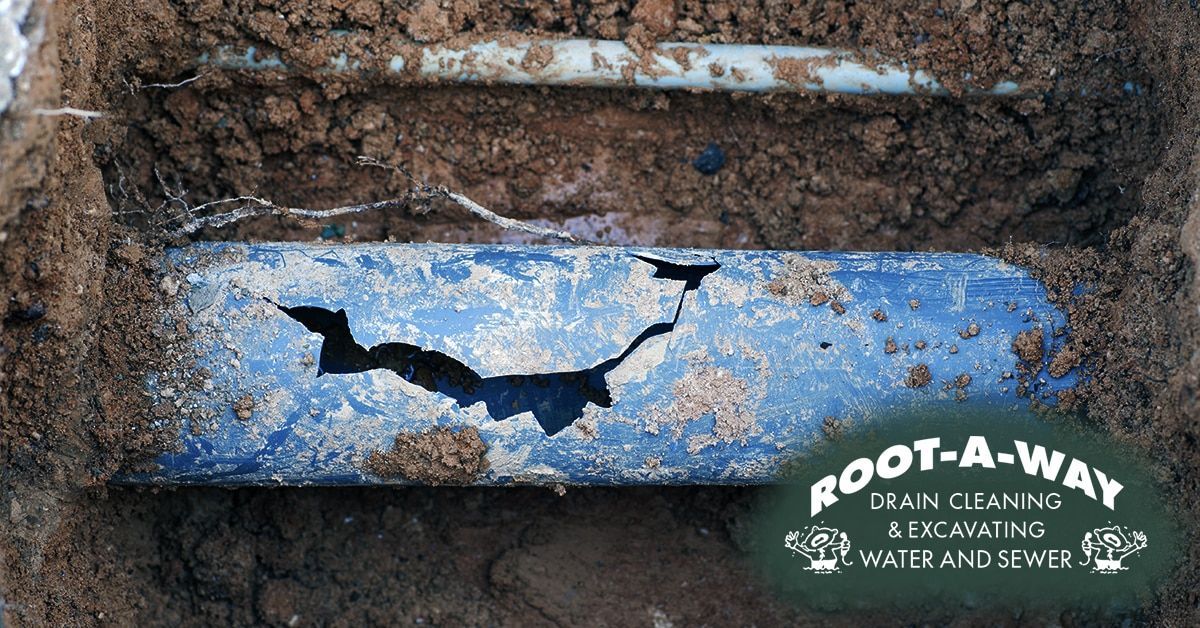 Blue buried pipe with a large crack in muddy soil