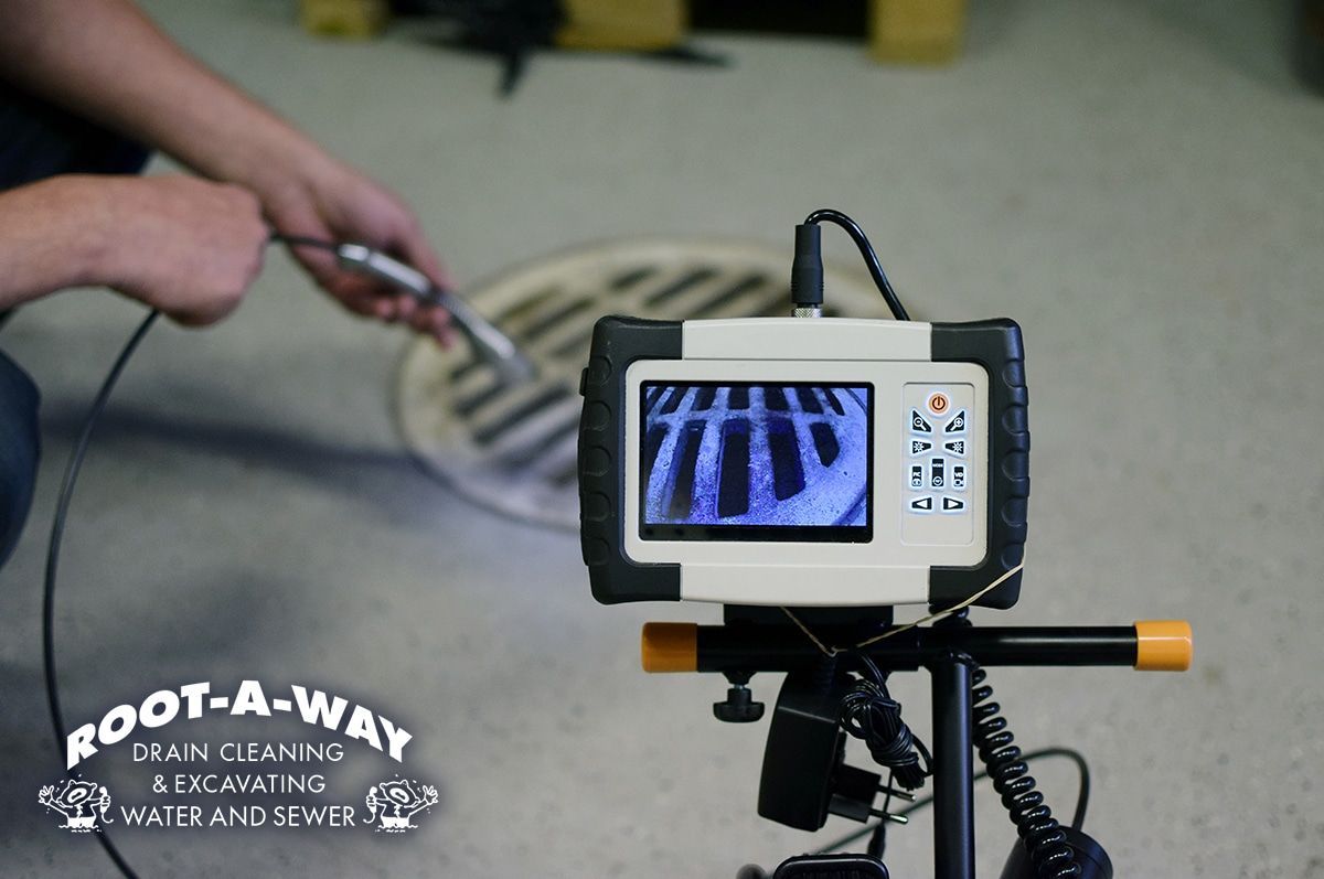 Worker inspecting a drainage system using a camera