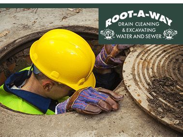 Worker in yellow hard hat in a manhole beside a sewer cover