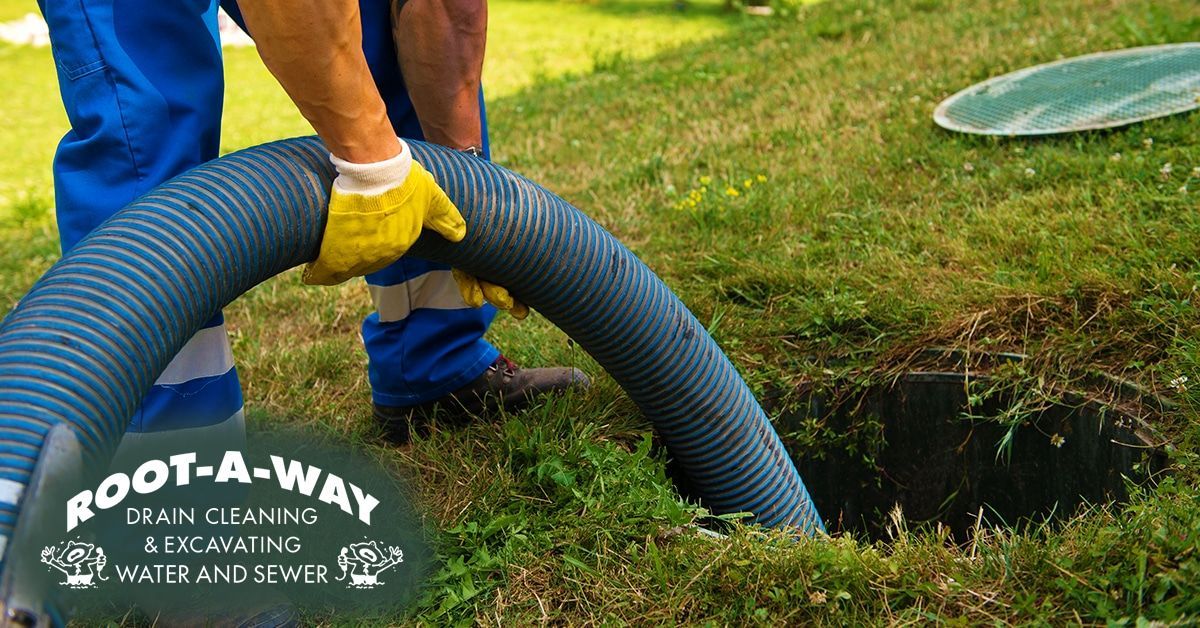 Worker using a hose to clear a lawn drainage hole Worker using a hose to clear a lawn drainage hole