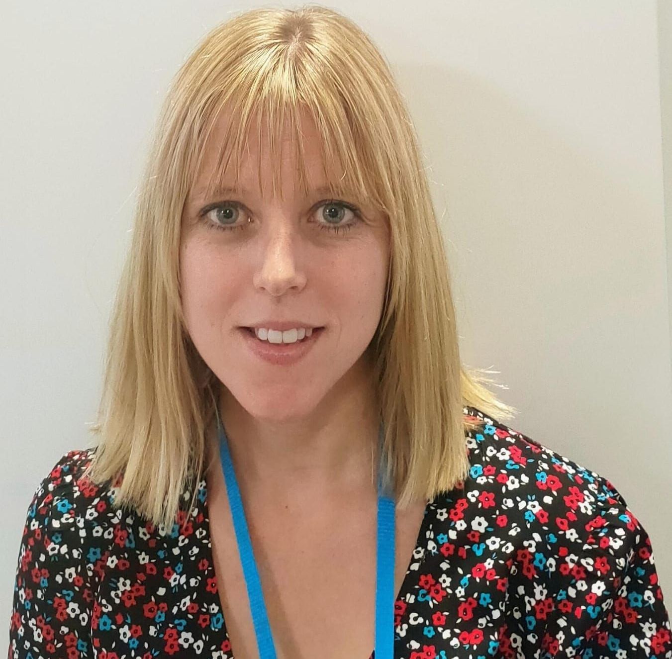A woman with blonde hair and a blue lanyard around her neck