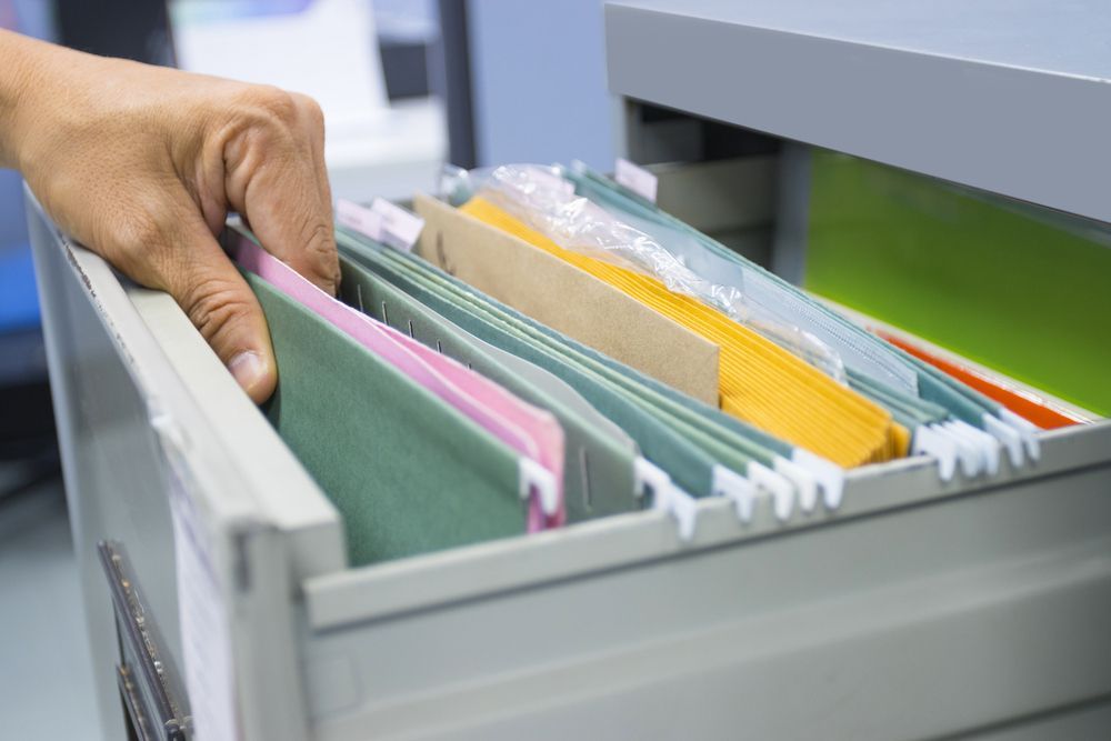 A person is taking a folder out of a filing cabinet.