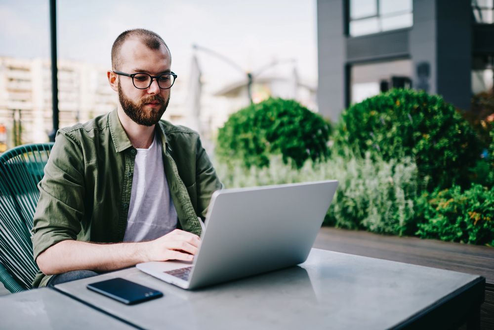 A man is sitting at a table using a laptop computer.