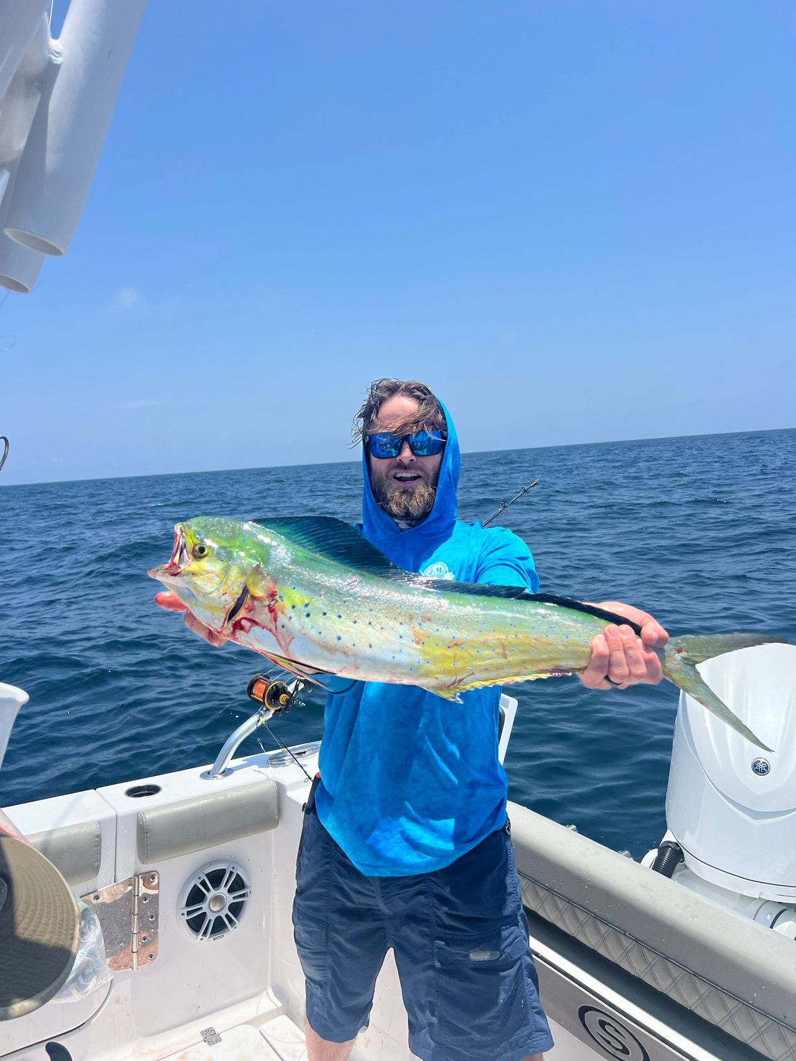 A man is holding a large fish on a boat in the ocean.