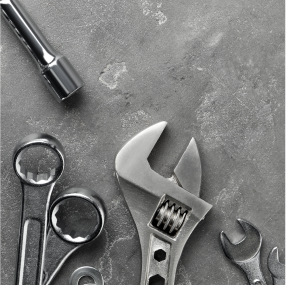 Close-up of various silver tools on a gray surface: wrenches and a socket. | RX Automotive