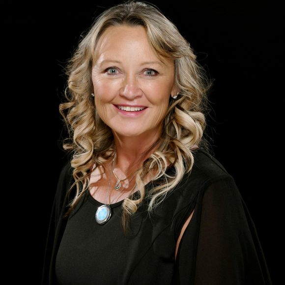 Smiling woman with blonde curls in a black top against a black background