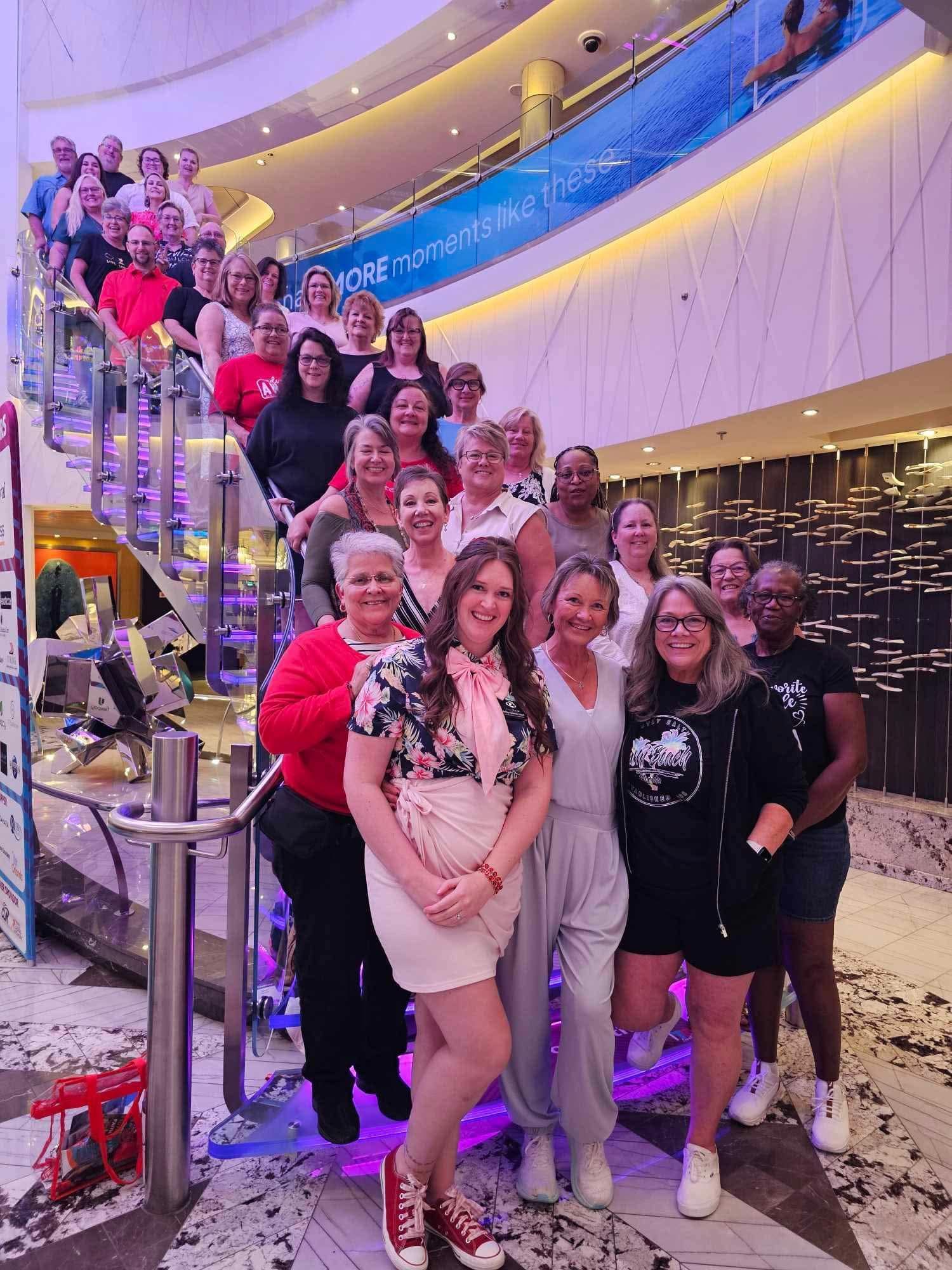 Group of people posing on indoor staircase with purple lighting and a large mural backdrop