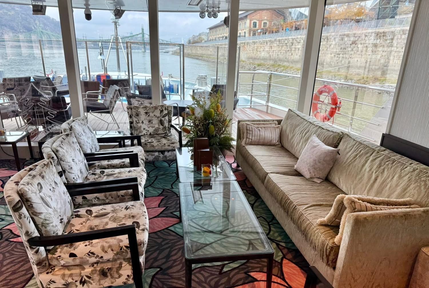 Covered patio seating area with wicker chairs, sofa, and glass table overlooking the water.