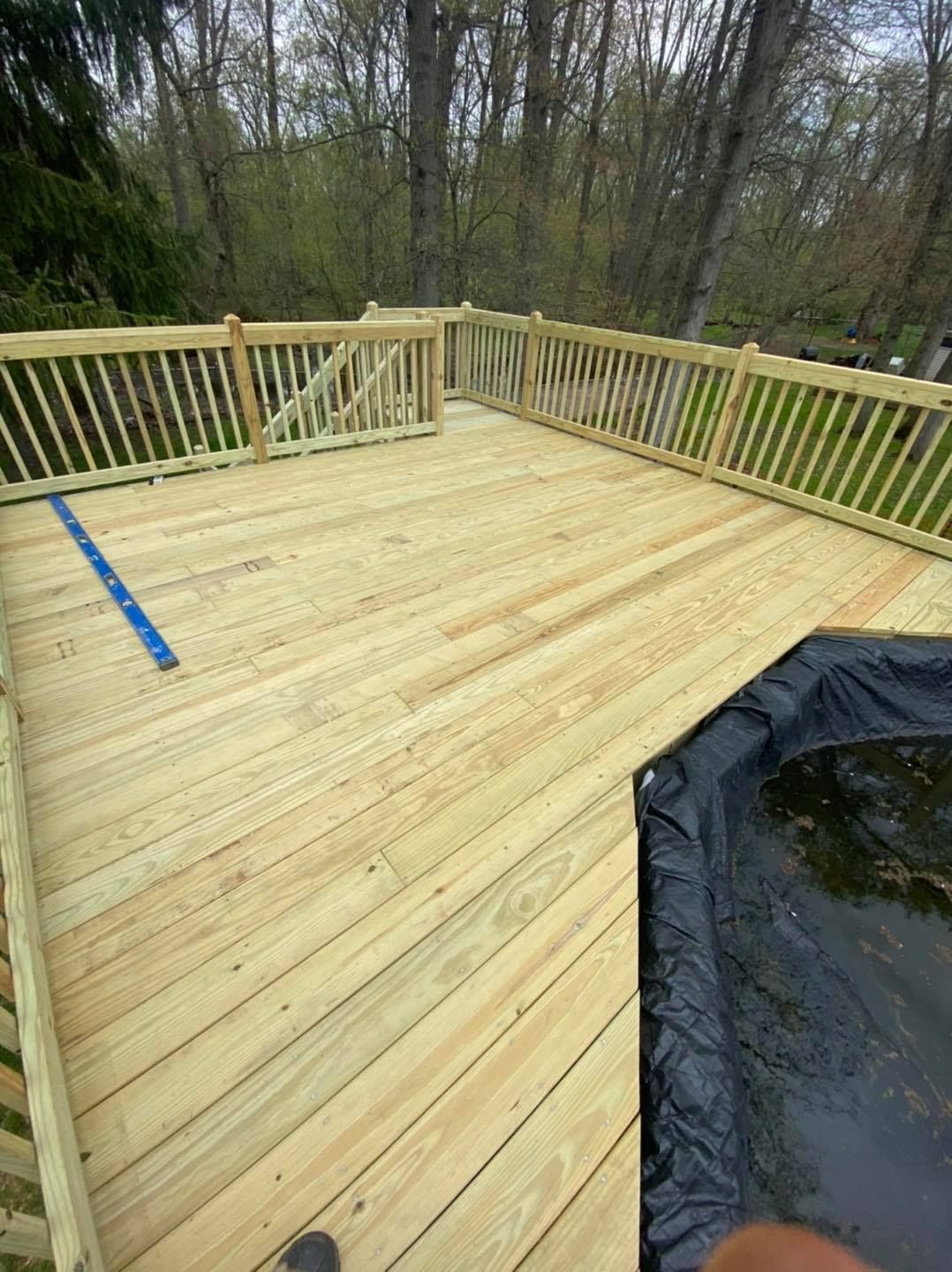 A person is standing on a wooden deck next to a hot tub.