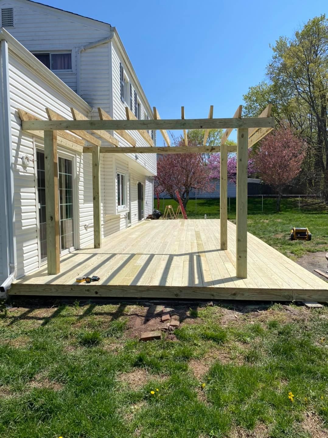 A wooden deck is being built in the backyard of a house.
