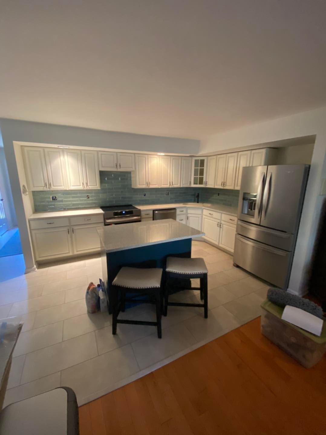 A kitchen with white cabinets , stainless steel appliances , and a large island.
