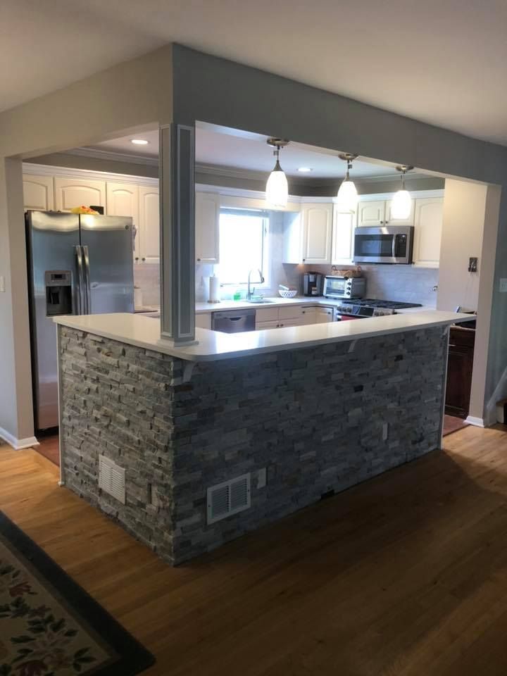 A kitchen with a stone counter top and a refrigerator