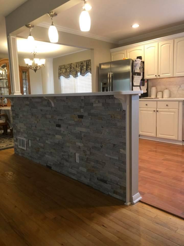 A kitchen with a brick wall between it and the dining room