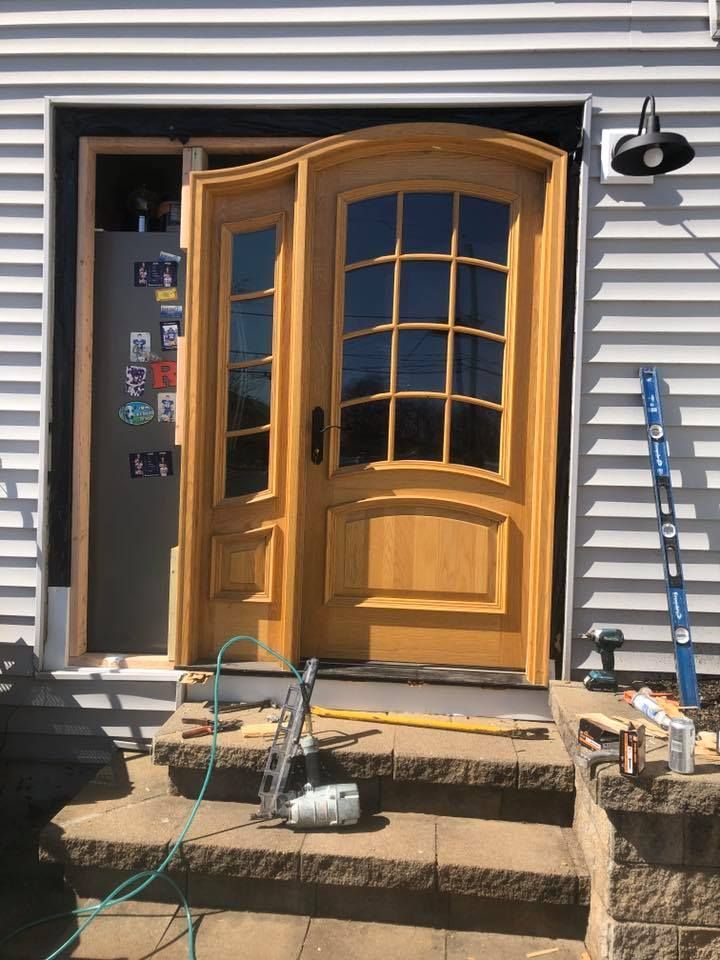 A wooden door is being installed on the front of a house.