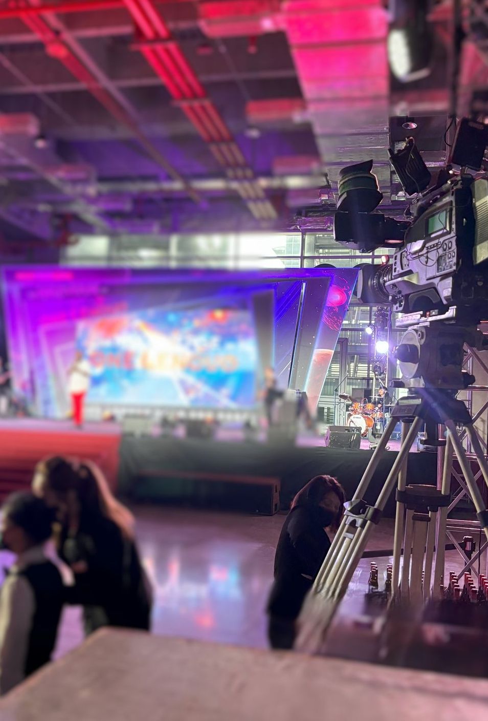 攝製組正在明亮的燈光和紫色背景下拍攝舞台表演。