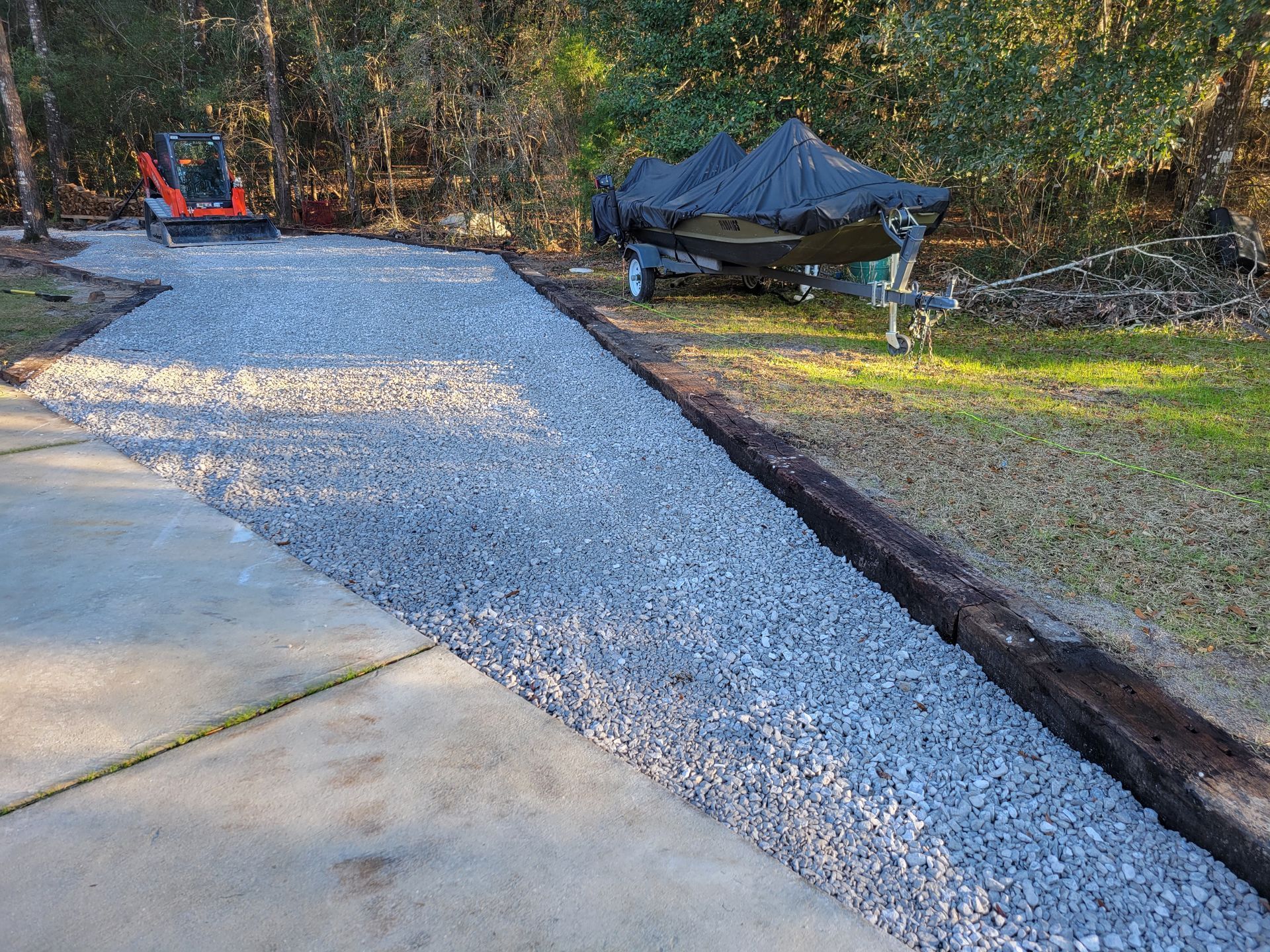 A gravel driveway with a boat in the background.