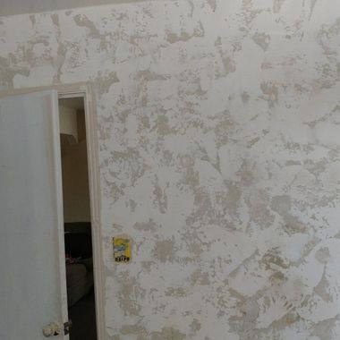 Textured wall with doorframe on left. White and light grey swirled pattern.
