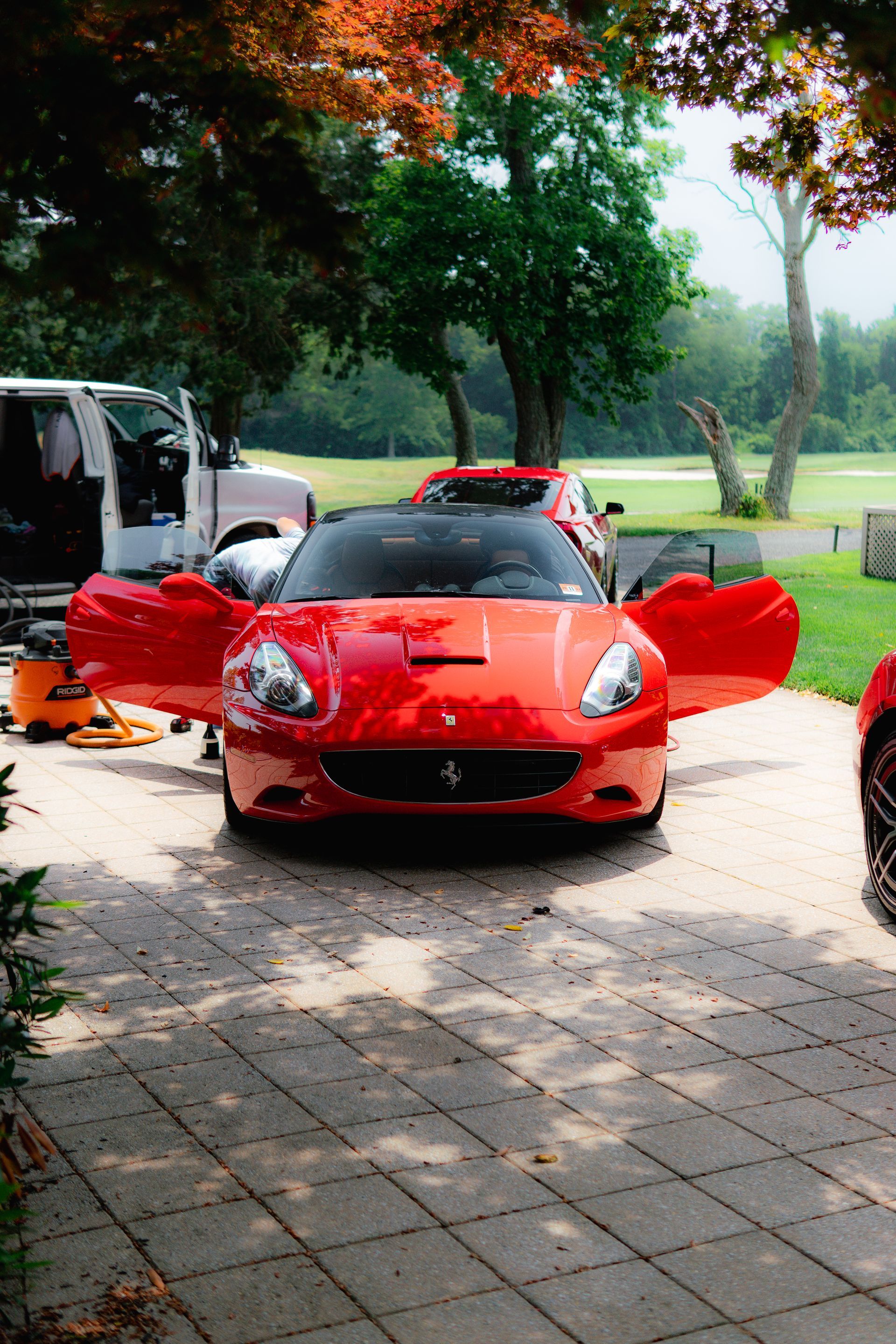 A red ferrari is parked in a driveway with its doors open