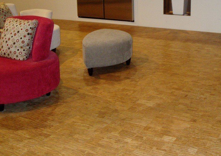 Intérieur avec sol en liège, fauteuil rouge et pouf gris.