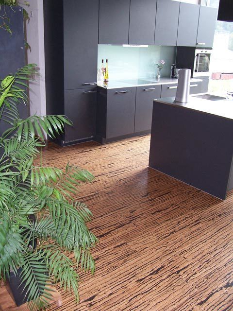 Cuisine moderne au sol en liège brun clair et armoires noires.