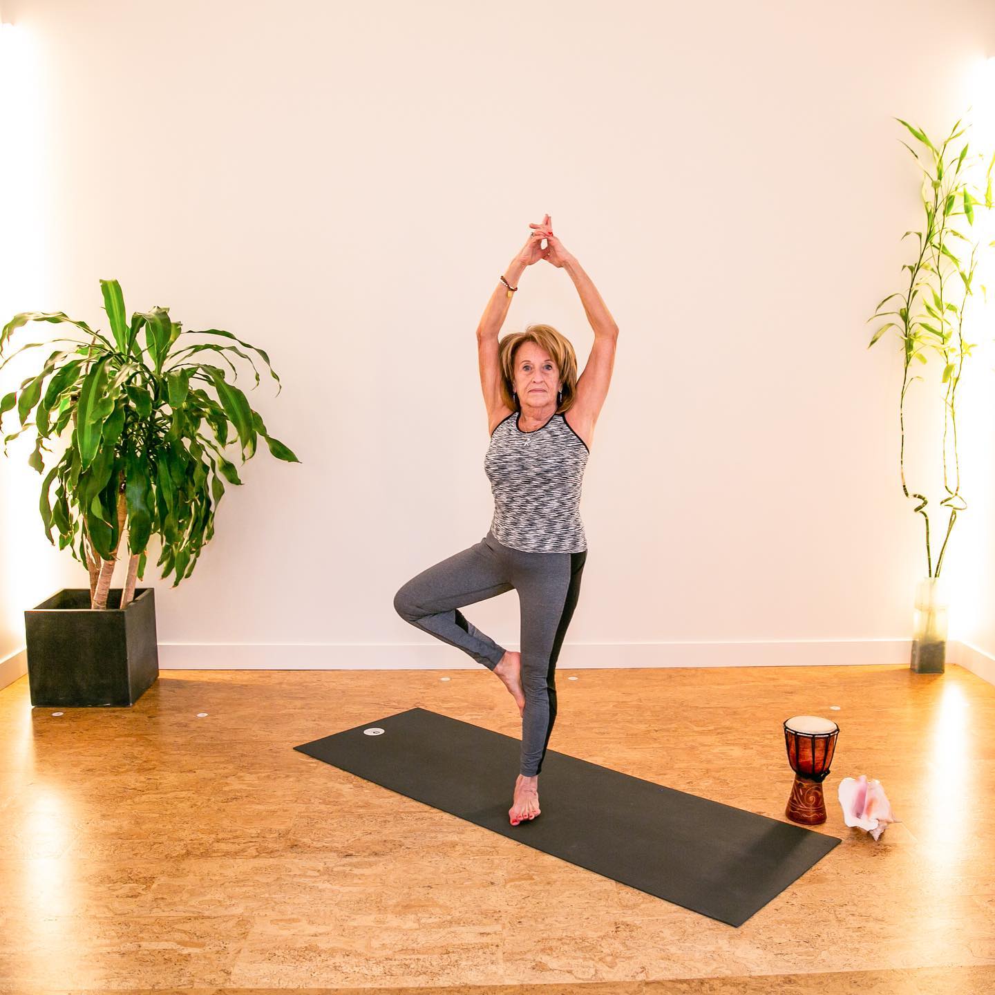 Une femme est debout sur une jambe sur un tapis de yoga