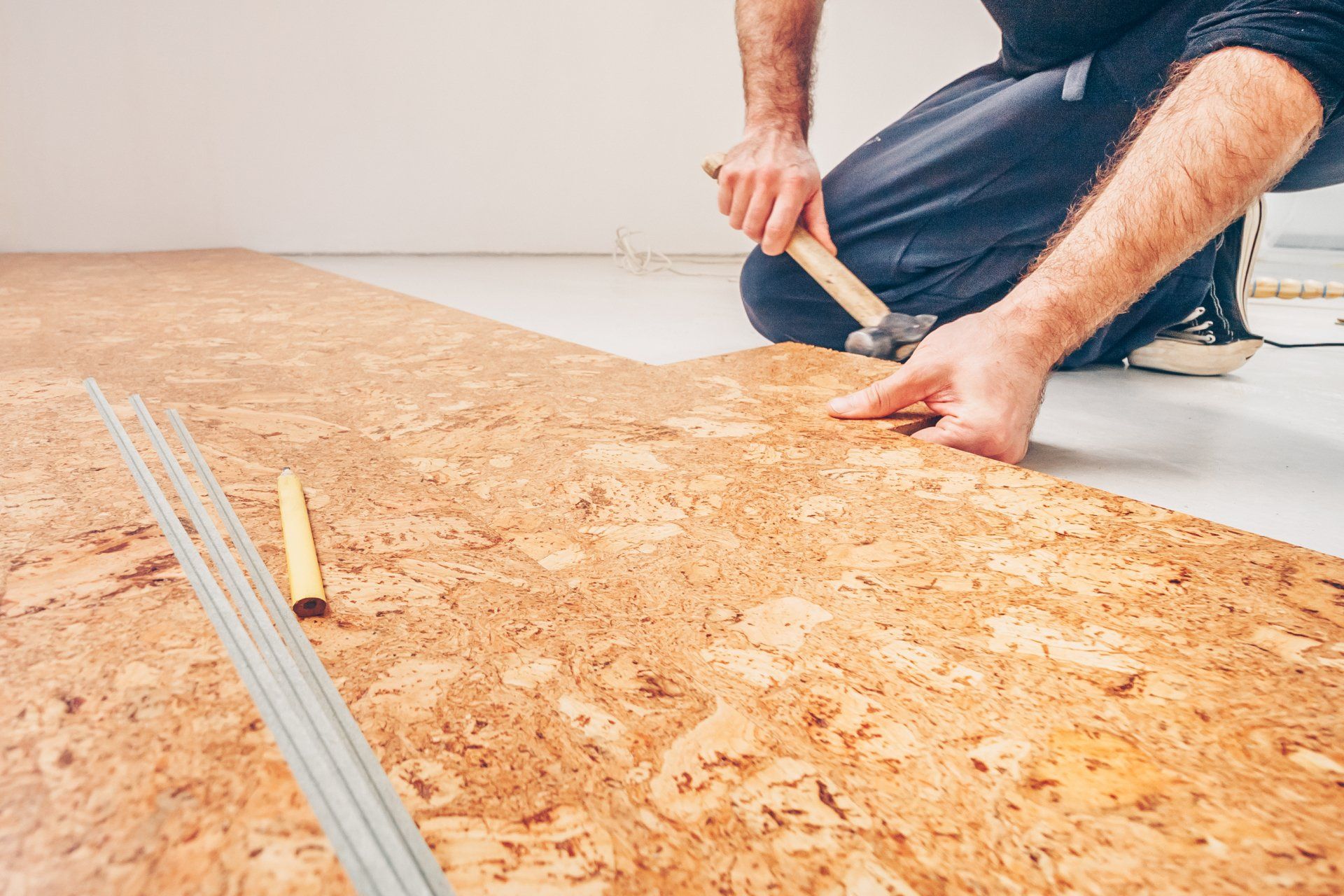 A man is installing a cork floor with a hammer.