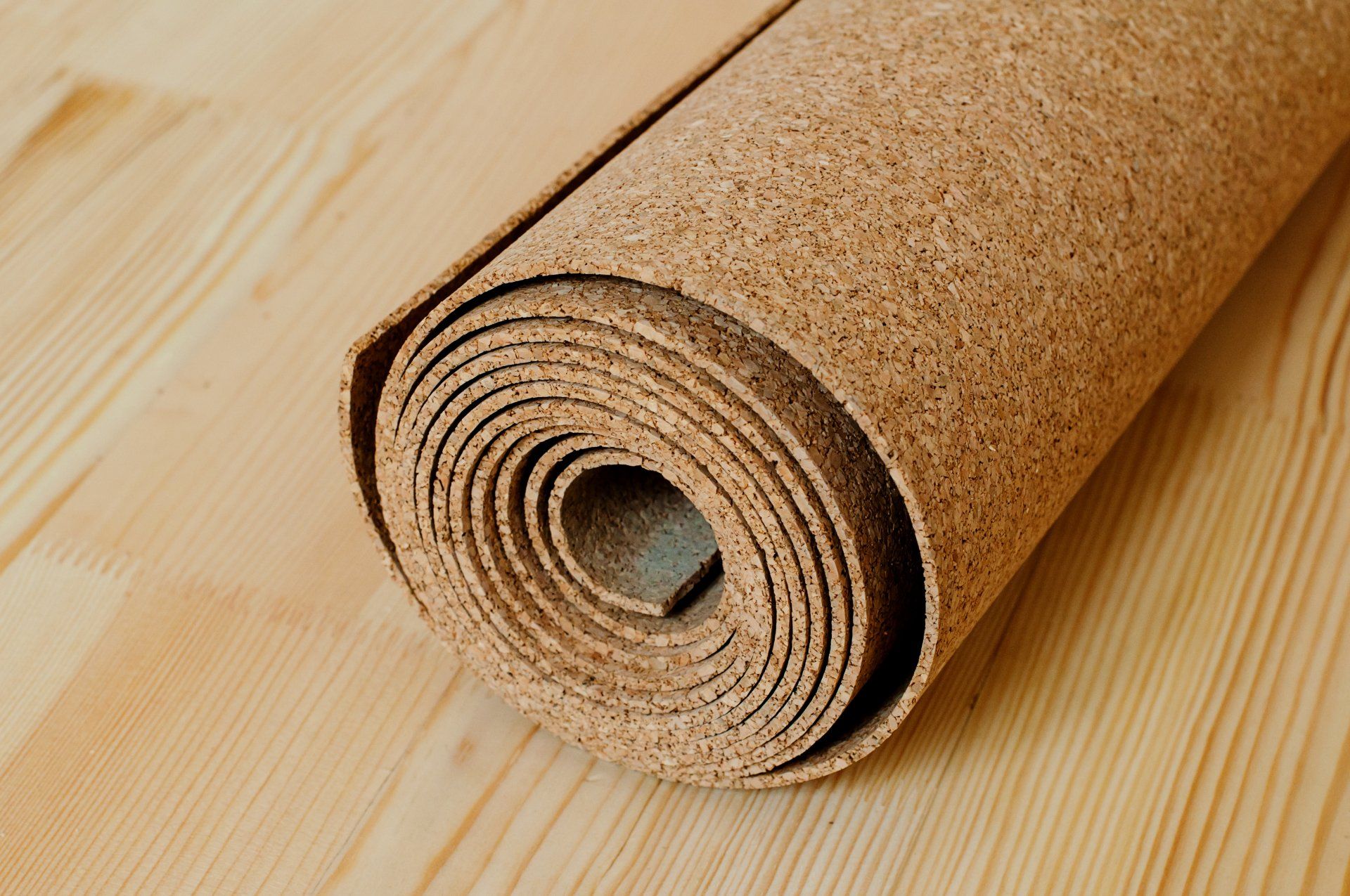 Tapis de liège enroulé sur un parquet clair.