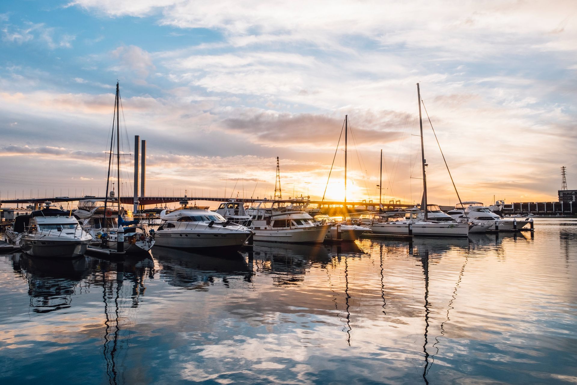 Boats docked in a harbor at sunset with reflections in the water.