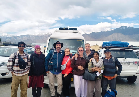 Group of travelers on a Leh Ladakh tour with mountain scenery and vehicles