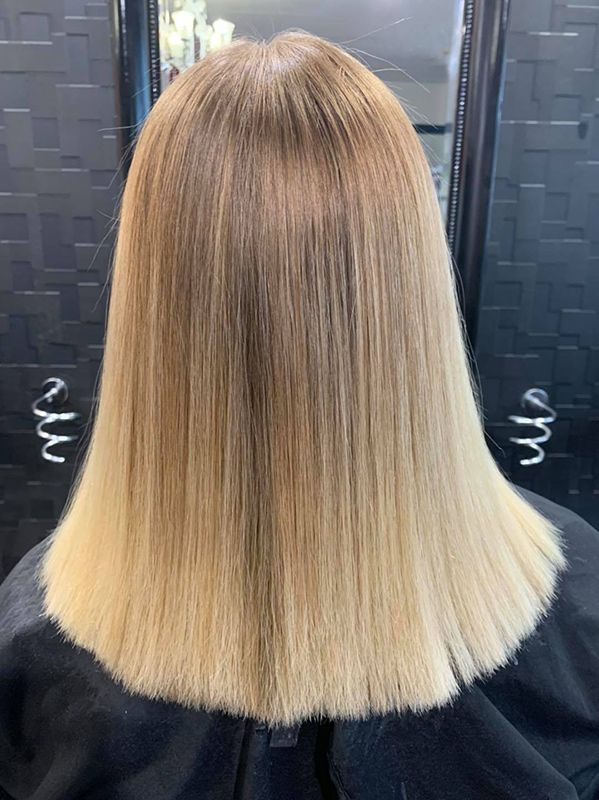 A Woman with Blonde Hair Is Sitting in A Chair in Front of A Mirror — Capello Hair Design in Port Macquarie, NSW