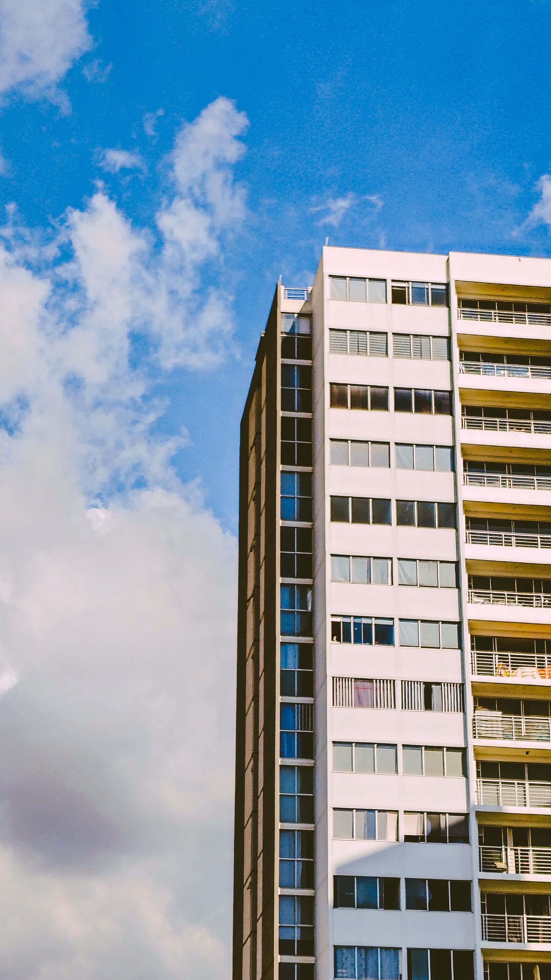 Tall apartment building against a blue sky with scattered clouds