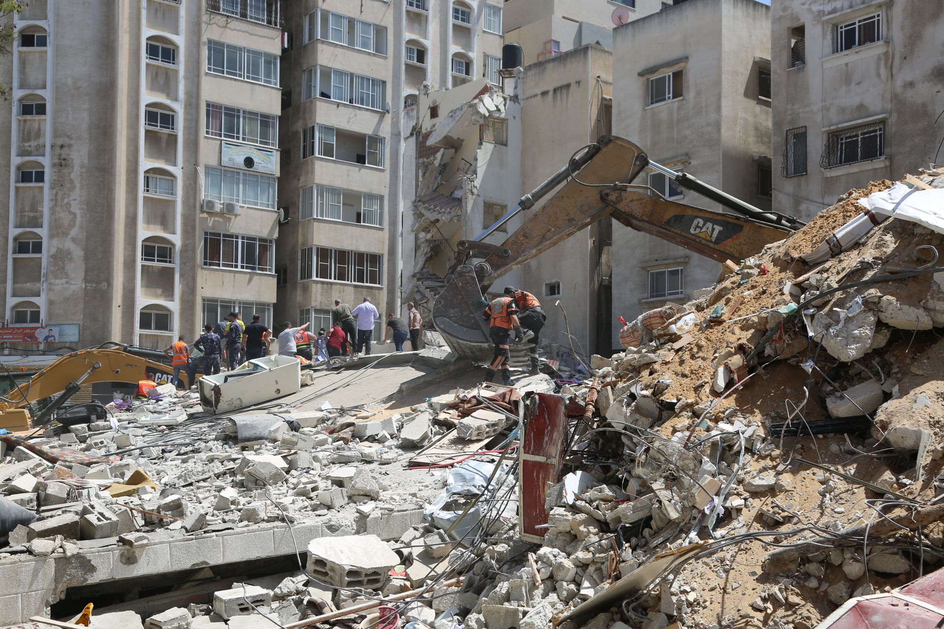 Collapsed building rubble with rescue workers and excavators in an urban disaster zone