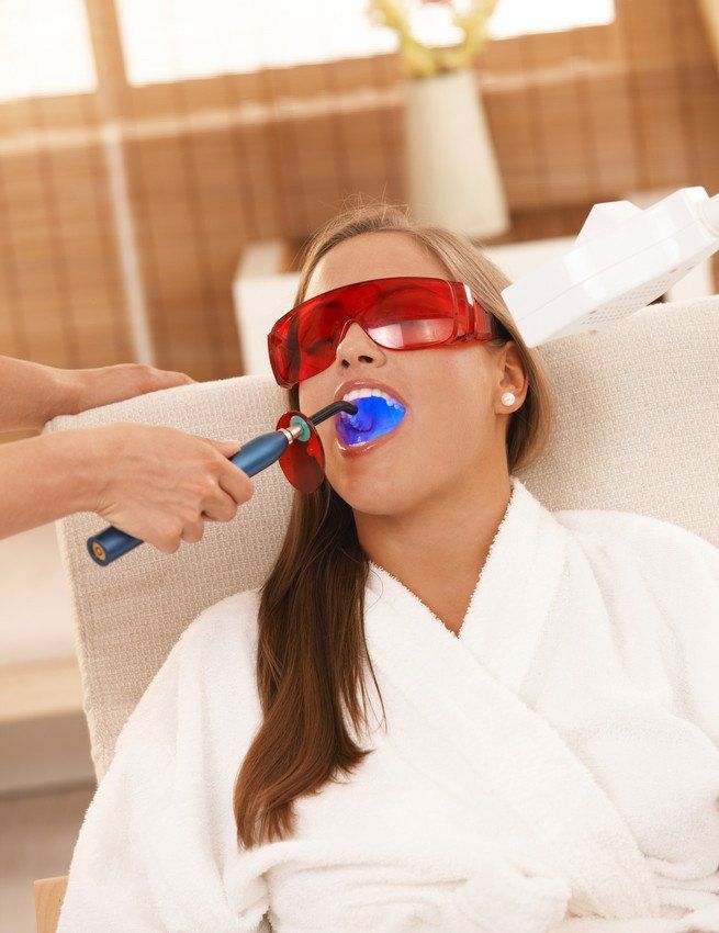 A woman wearing sunglasses is getting a dental treatment