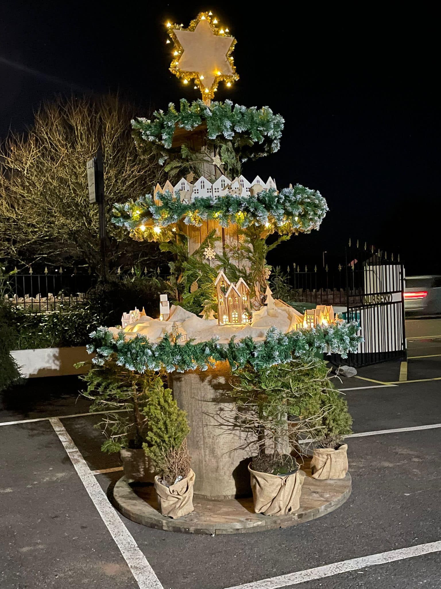 A christmas tree in a parking lot with a star on top