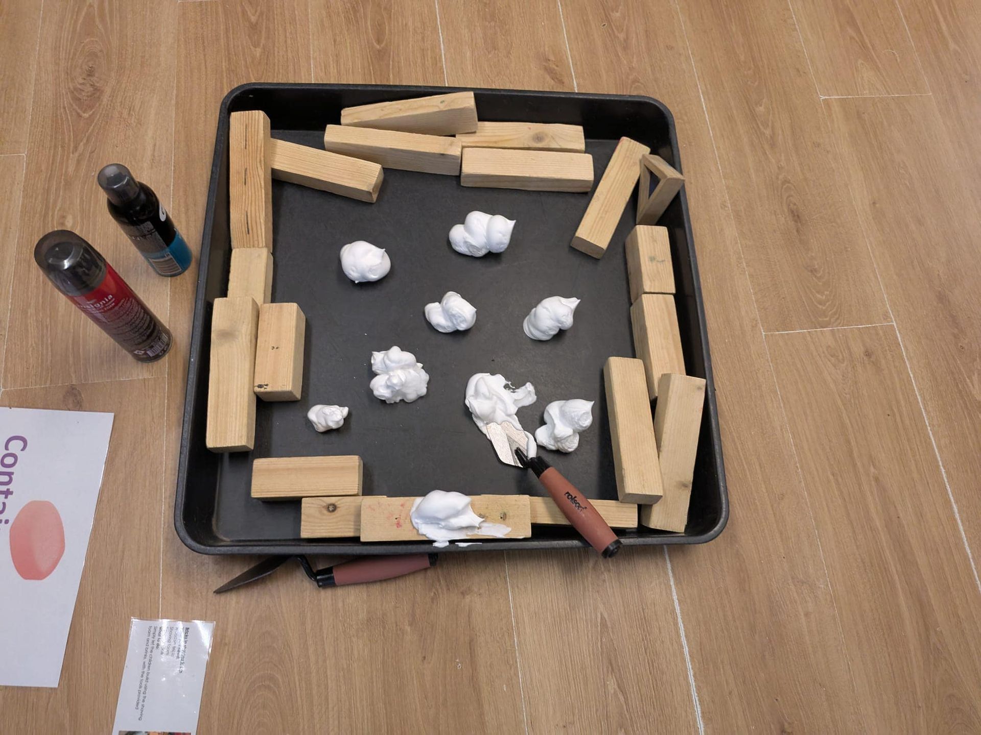 A tray of wooden blocks with a spatula and a bottle of spray paint